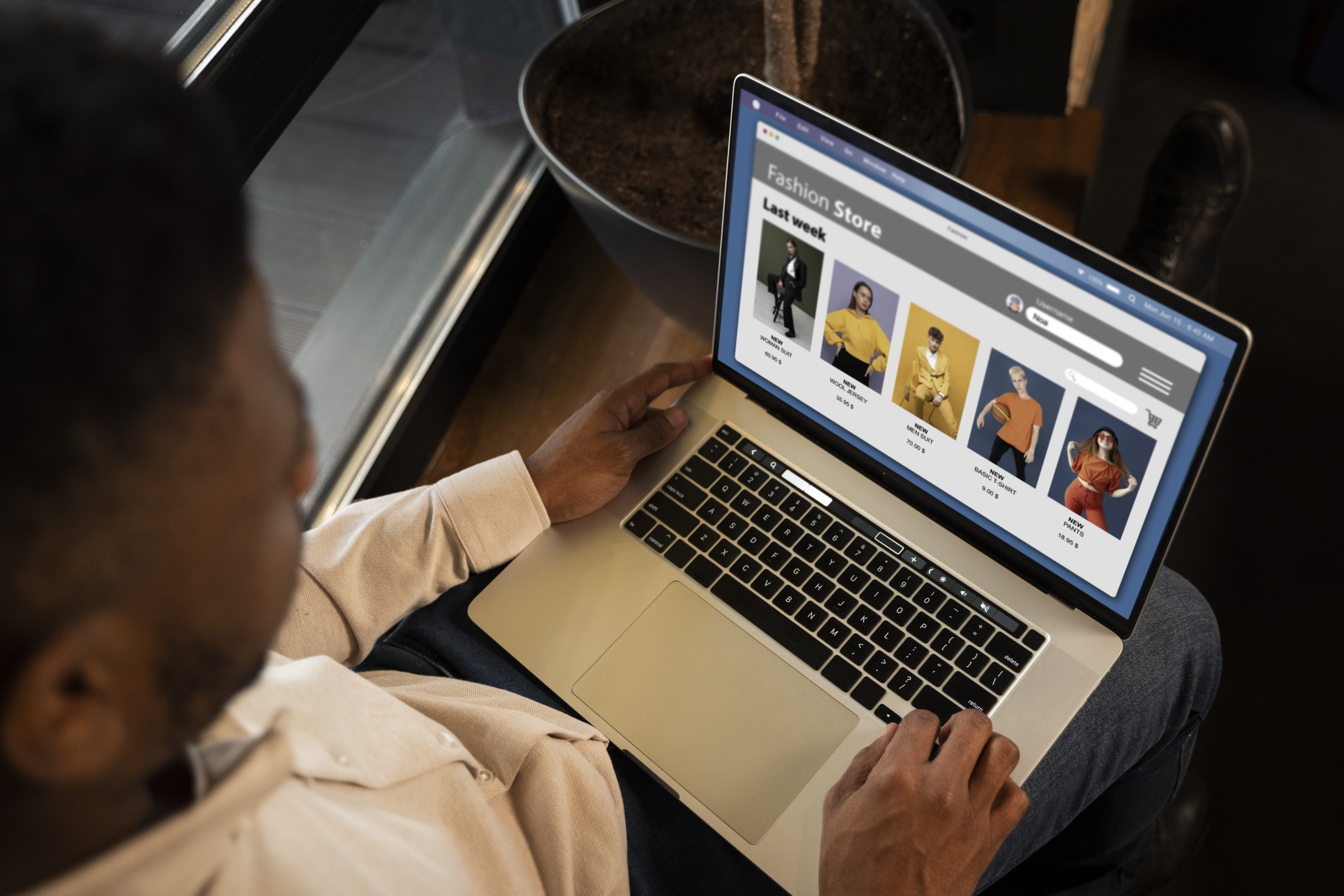 Women sitting on a couch looking at a laptop screen and she has a cup in her hand.